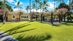 A resort with a covered outdoor area, palm trees, and a well-maintained lawn. - Fairway Villas Waikoloa A21 (Waikoloa)