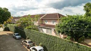 Un barrio residencial con una casa de techo de tejas, un camino de entrada con coches aparcados y un seto bien cuidado.