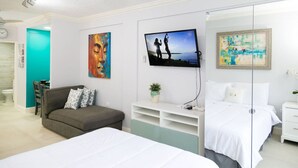Un dormitorio moderno con una cama, un sofá, un televisor y obras de arte en las paredes.