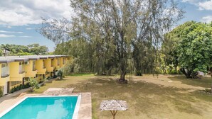 Zona de piscina con un edificio amarillo al fondo.