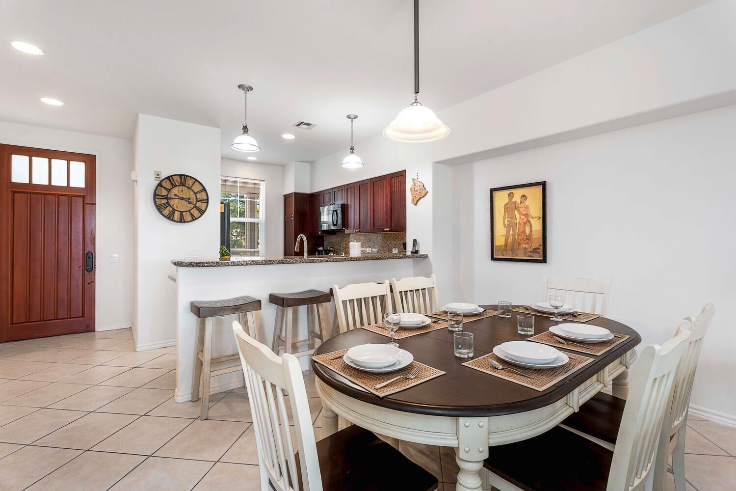 A dining area with a round table, chairs, and a kitchen in the background.