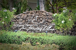 Welcome to The Fairway Villas, surrounded by lush greenery and a serene stone wall.