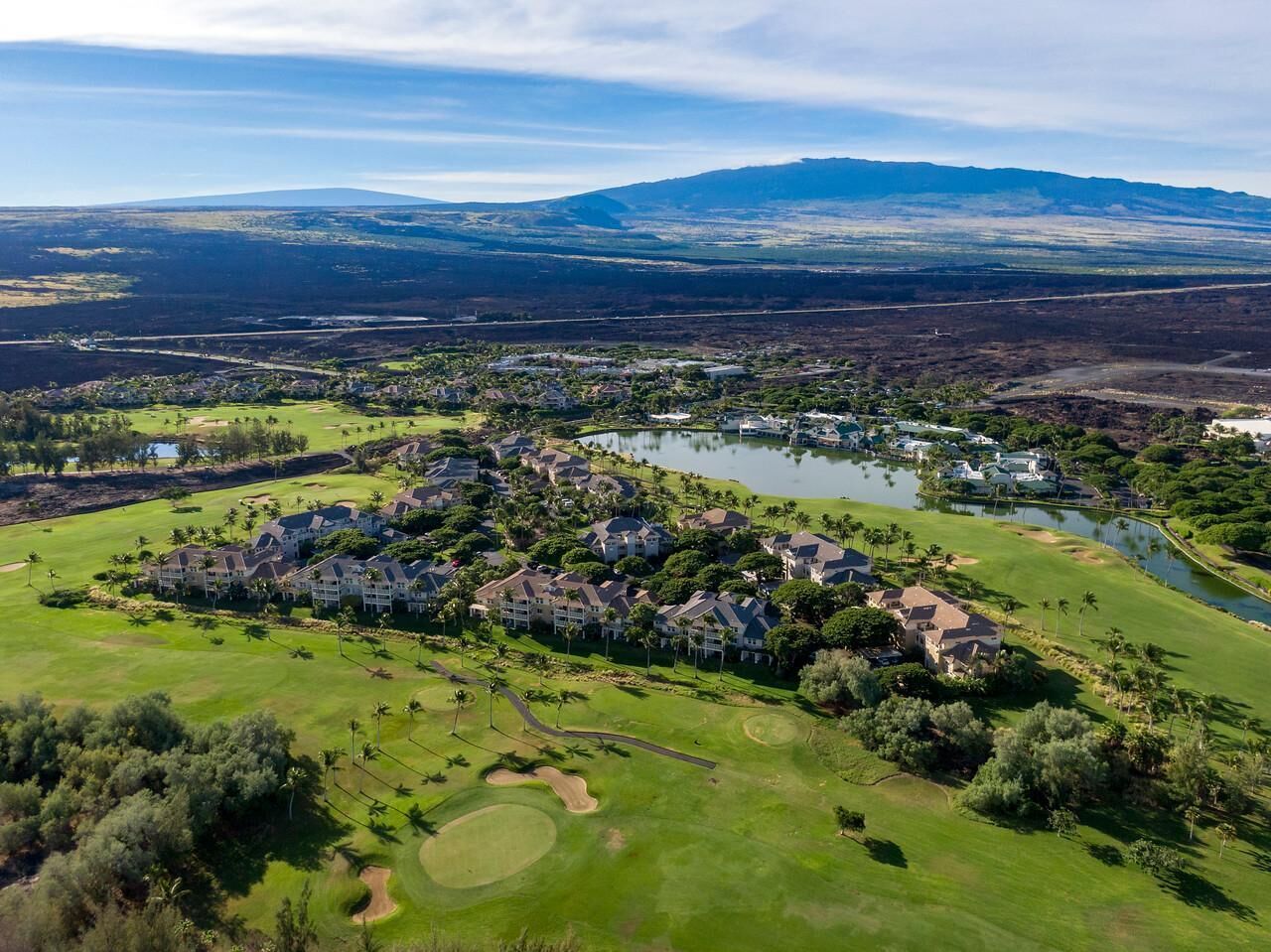 An aerial view of a golf resort with multiple buildings, a lake, and surrounding greenery.