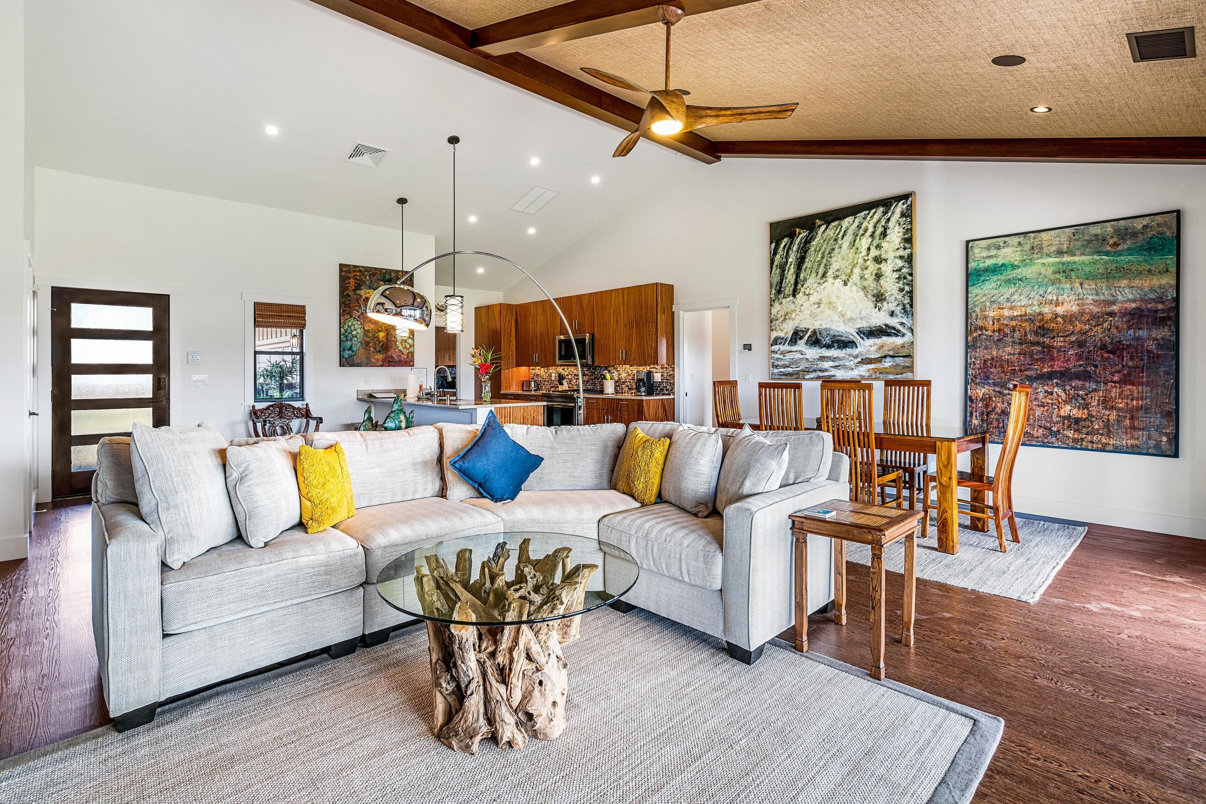 A spacious living room with a sectional sofa, a glass coffee table, and a dining area with wooden chairs.