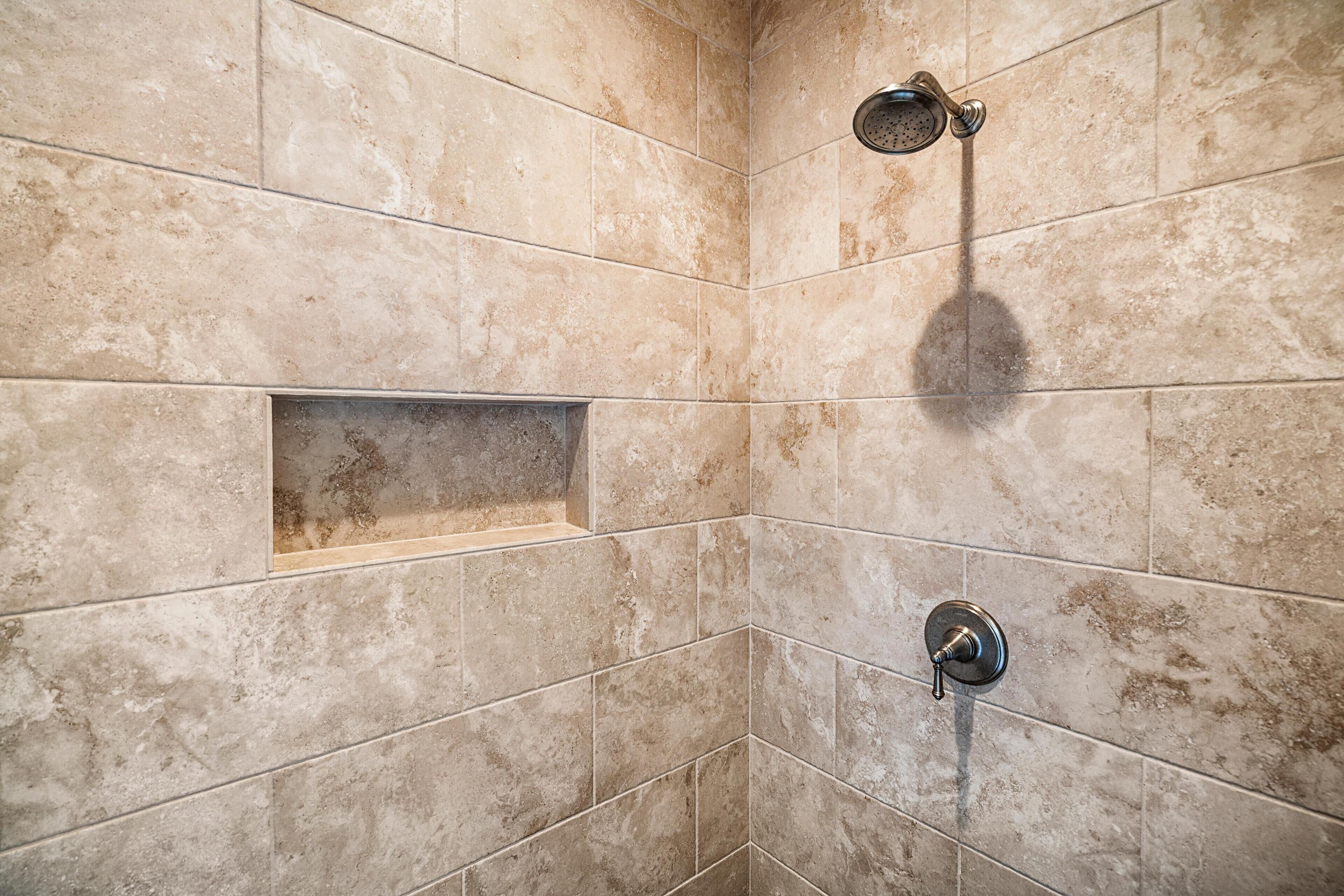 A shower area with beige tiles and a built-in bench.