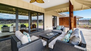An outdoor patio with wicker furniture, a ceiling fan, and a view of the landscape.