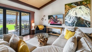 A living room with a large TV, comfortable seating, and a view of the outdoors.