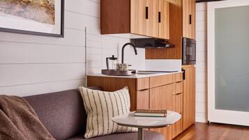 A compact kitchen with wooden cabinets, a modern faucet, and a small table with a book.