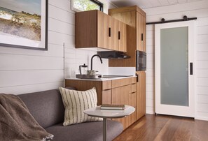 A modern kitchen with wooden cabinets, a built-in microwave, and a glass door.