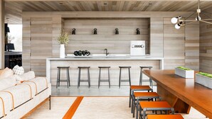 A modern kitchen with a wooden ceiling, a central island with stools, and a bar area. - AutoCamp Cape Cod (Falmouth)