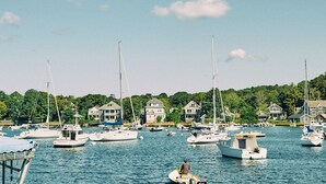 A marina with multiple sailboats docked, surrounded by houses and greenery. - AutoCamp Cape Cod (Falmouth)