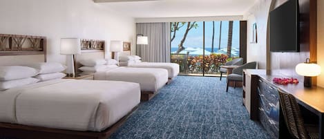 A hotel room with two beds, a desk, a chair, a TV, and a balcony with a view of the ocean.