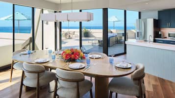 Een eetgedeelte met een grote tafel voor zes personen, met uitzicht op een balkon en de oceaan.