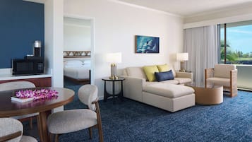 A hotel room with a sofa, armchairs, a dining table, and a TV.