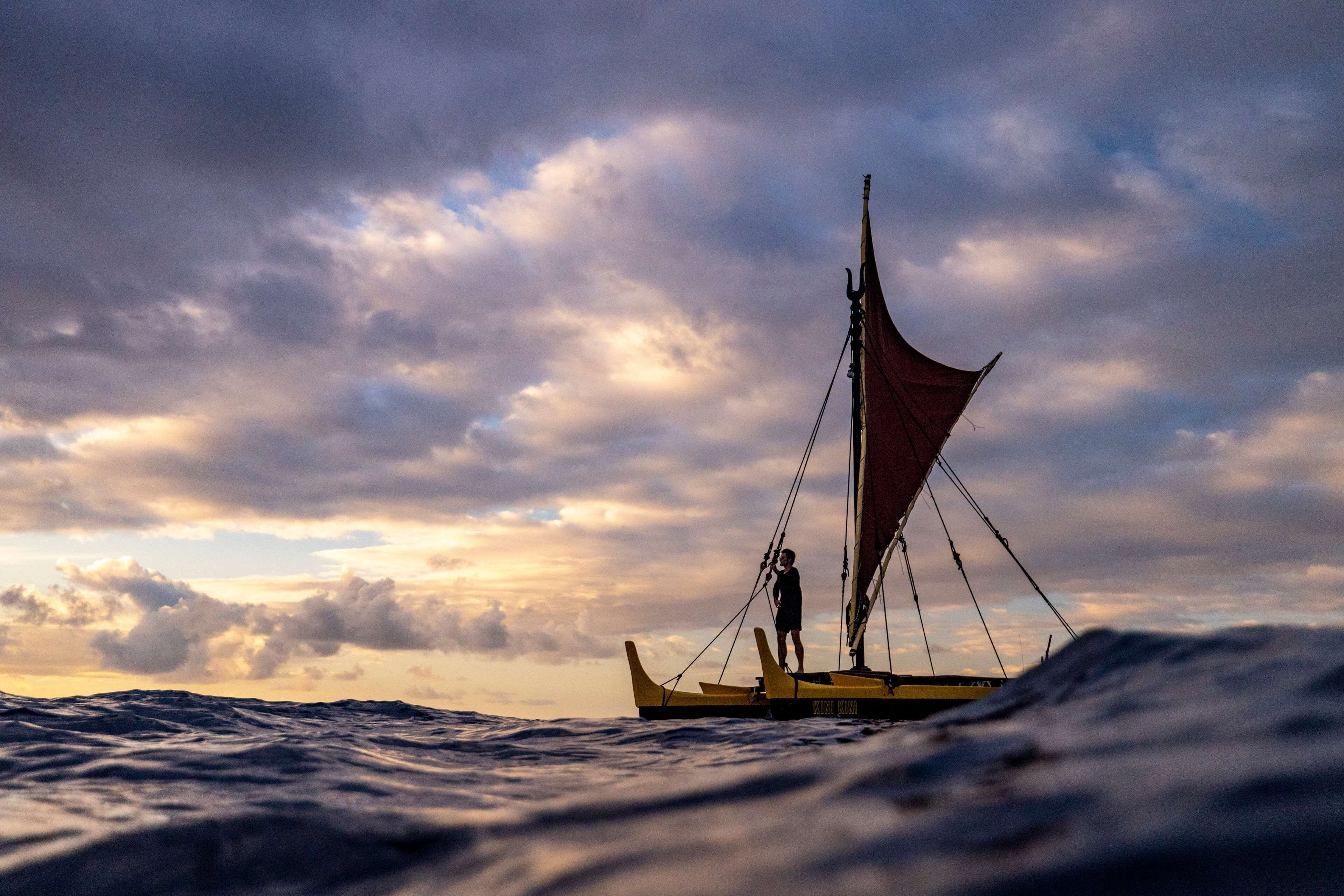 A sailboat on the water with a person standing on the deck.
