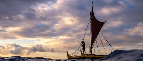 A sailboat on the water with a person standing on the deck.