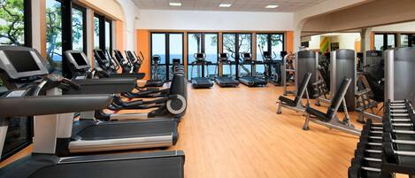 A gym with multiple treadmills, exercise bikes, and weight machines.