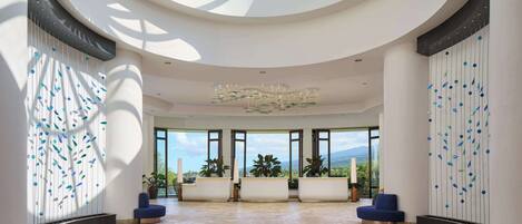 A spacious lobby with a high ceiling, large windows, and a central chandelier.