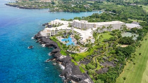 A coastal resort with a large pool, multiple buildings, and lush greenery.