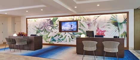 A reception area with a large TV, two reception desks, and wicker chairs.