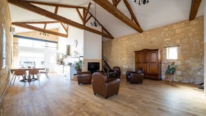 A spacious living area with wooden floors, a fireplace, leather sofas, and a stone wall. - Domaine du chauvet (Ambares-et-Lagrave)