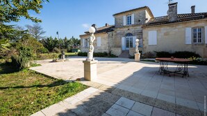 A courtyard with a stone building, a statue, and a table. - Domaine du chauvet (Ambares-et-Lagrave)
