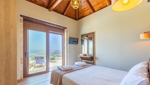 A bedroom with a bed, a wooden ceiling, a TV, and a view through a glass door. - Heated pool + hydro-massage ★ Sea view ★ Near Falasarna (Phalasarna)