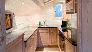 Une cuisine étroite avec des meubles de rangement en bois et un plan de travail noir.