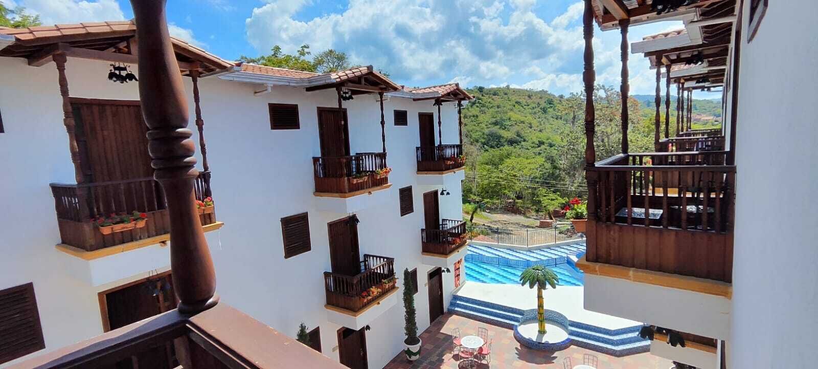 Un edificio de varios pisos con balcones, una piscina y vistas a un paisaje verde exuberante.