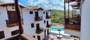 Un immeuble à plusieurs étages doté de balcons, d’une piscine et offrant une vue sur un paysage verdoyant.