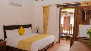 A bedroom with a bed, bedside table, lamp, and a view of an outdoor patio area.
