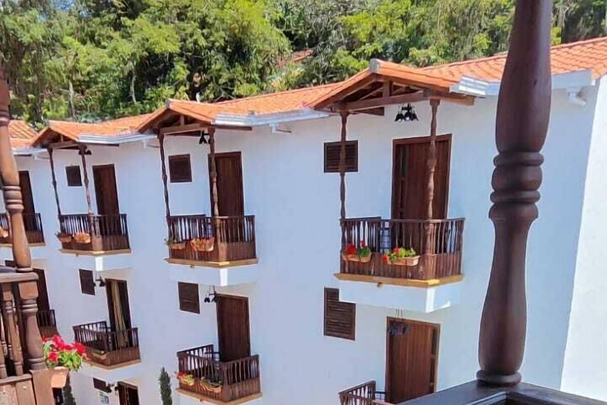 Ein Balkon mit Holzwertkasten, einem Stuhl und Blick auf ein Gebäude mit mehreren Balkonen und einer gefliesten Terrasse.