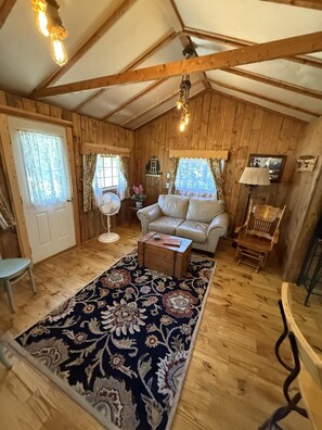 A cozy cabin interior with wooden walls, a sofa, a small table, and a fan. - Little Mosser-Awesome Views! Very Quiet! (Estes Park)