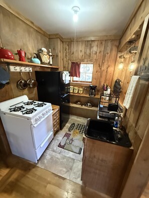 A compact kitchen with a stove, refrigerator, and sink.