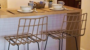 A kitchen with a wooden countertop, two metal chairs, and a small table with bowls and a basket. - Cozy studio in the heart of Recoleta (CABA)
