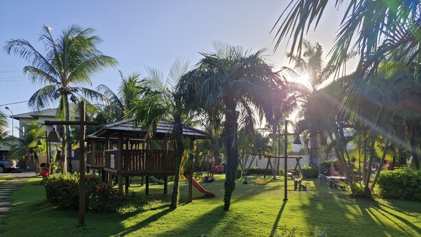 A playground with a wooden structure, palm trees, and a grassy area. - ⭐🌴 House in Guarajuba, 3 Bedrooms with Pool, 150m from the Sea (Guarajuba)