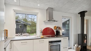 A modern kitchen with a large window, a built-in oven, and a black wood-burning stove. - Amazing home in Hjerm with house a panoramic view (Hjerm)