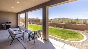 An outdoor patio with a grill, seating, and a view of a landscaped yard. - Hideaway On The 2nd Green (St. George)