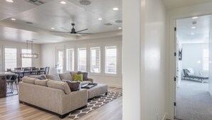 A spacious living room with a large sofa, a dining area, and a ceiling fan. - Hideaway On The 2nd Green (St. George)