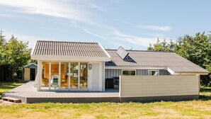 Moderni talo, jossa on suuri lasiovella varustettu sisäänkäynti, terassi ja satelliittiantenni.