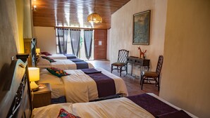 Une chambre d’hôtel avec trois lits, un bureau et une chaise.