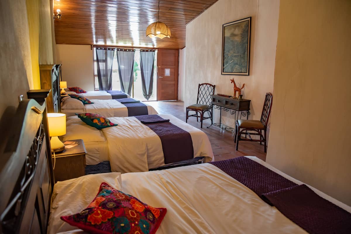 Een hotelkamer met drie bedden, een bureau en een stoel.