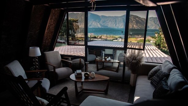 Un salon chaleureux avec une grande fenêtre donnant sur une côte montagneuse.