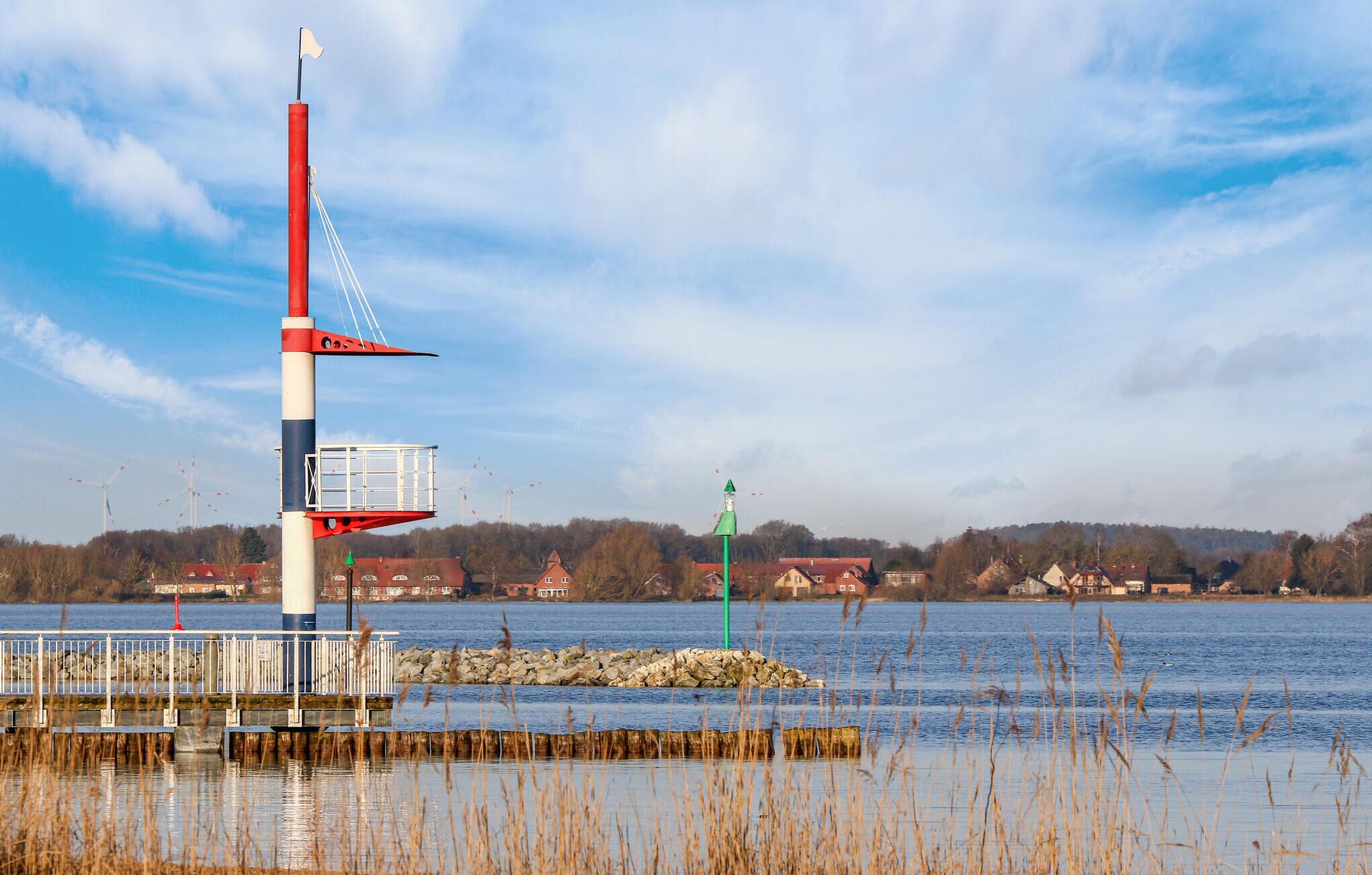 A lighthouse with a red and white structure, a green sign, and a rocky outcrop in the foreground.