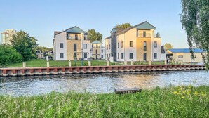A riverside residential area with modern buildings, a bridge, and lush greenery. - Cozy apartment in Rechlin with lake view (Rechlin)