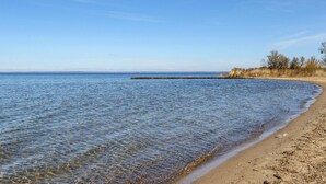A clear beach with calm waters, a wooden pier, and a sandy shore. - Cozy apartment in Rechlin with lake view (Rechlin)