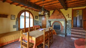 A rustic dining area with a brick fireplace, wooden furniture, and stone walls. - La Casella- La Terrazza (Castelfranco di Sopra)
