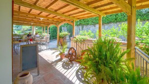An outdoor patio area with wooden beams, tables, chairs, and potted plants. - La Casella- La Terrazza (Castelfranco di Sopra)