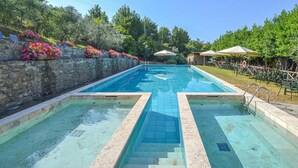 A rectangular swimming pool with a stone wall on one side and a grassy area with umbrellas on the other. - La Casella- La Terrazza (Castelfranco di Sopra)