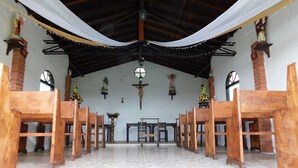 A church interior with wooden pews, a central altar, and religious statues.